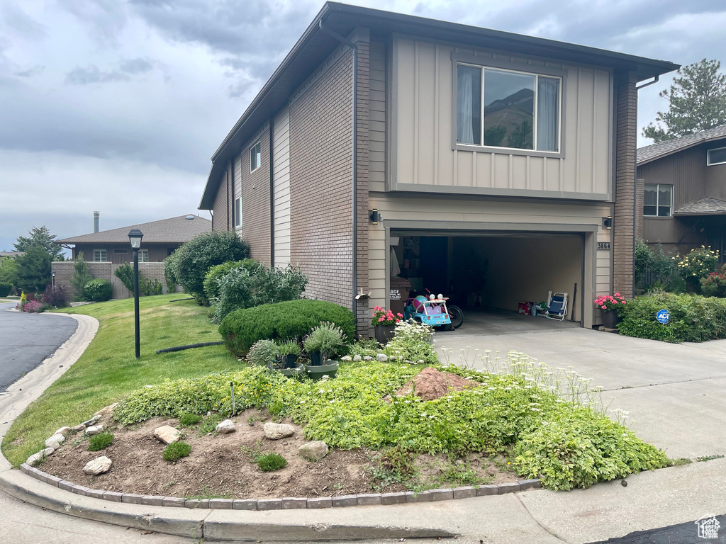 View of home's exterior with a garage, board and batten siding, driveway, and a yard
