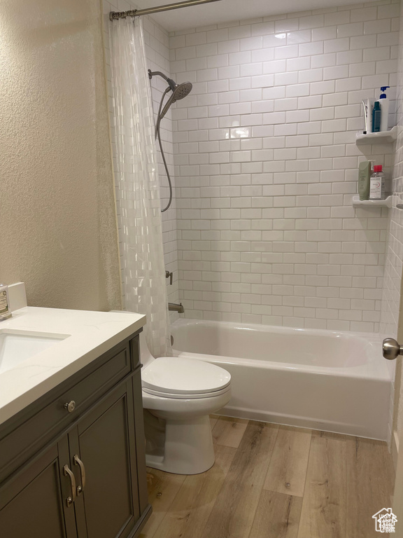 Full bath featuring wood finished floors, vanity, shower / bath combo, and a textured wall