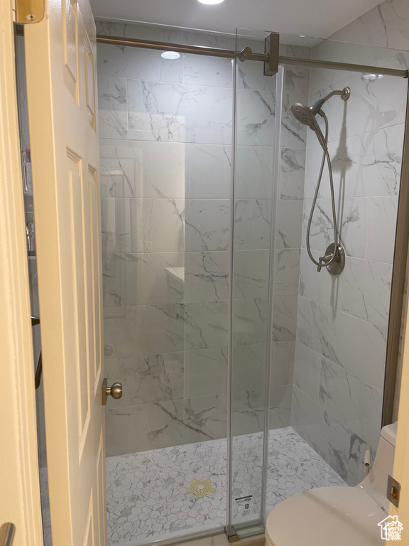 Full bathroom with toilet and a marble finish shower