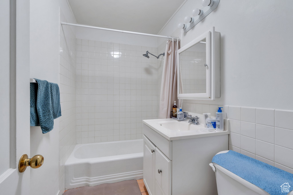 Bathroom with vanity, shower / tub combo, and tile walls