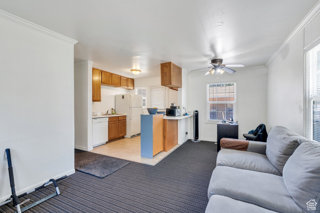 Kitchen with white appliances, open floor plan, ceiling fan, light carpet, and ornamental molding