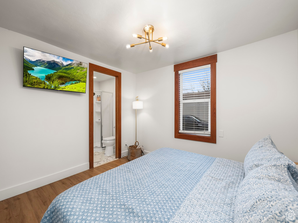 Bedroom with a chandelier, wood finished floors, and connected bathroom