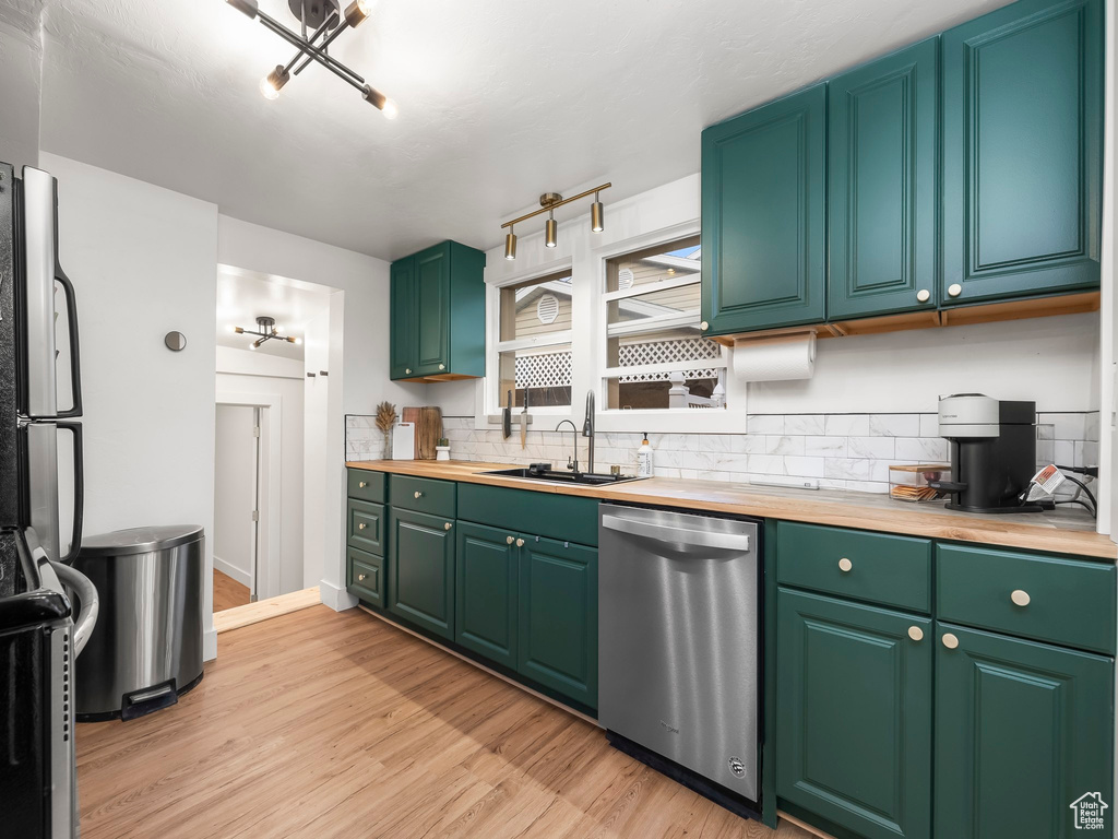 Kitchen featuring stainless steel dishwasher, butcher block counters, light wood-style flooring, and tasteful backsplash