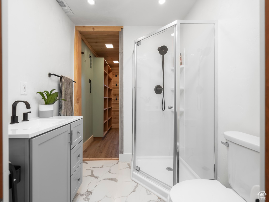 Bathroom with marble look tiles, a stall shower, vanity, and recessed lighting