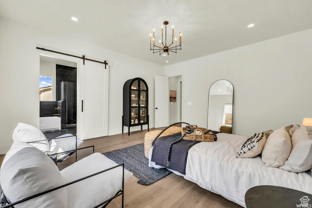 Bedroom featuring a barn door, a chandelier, wood finished floors, and recessed lighting