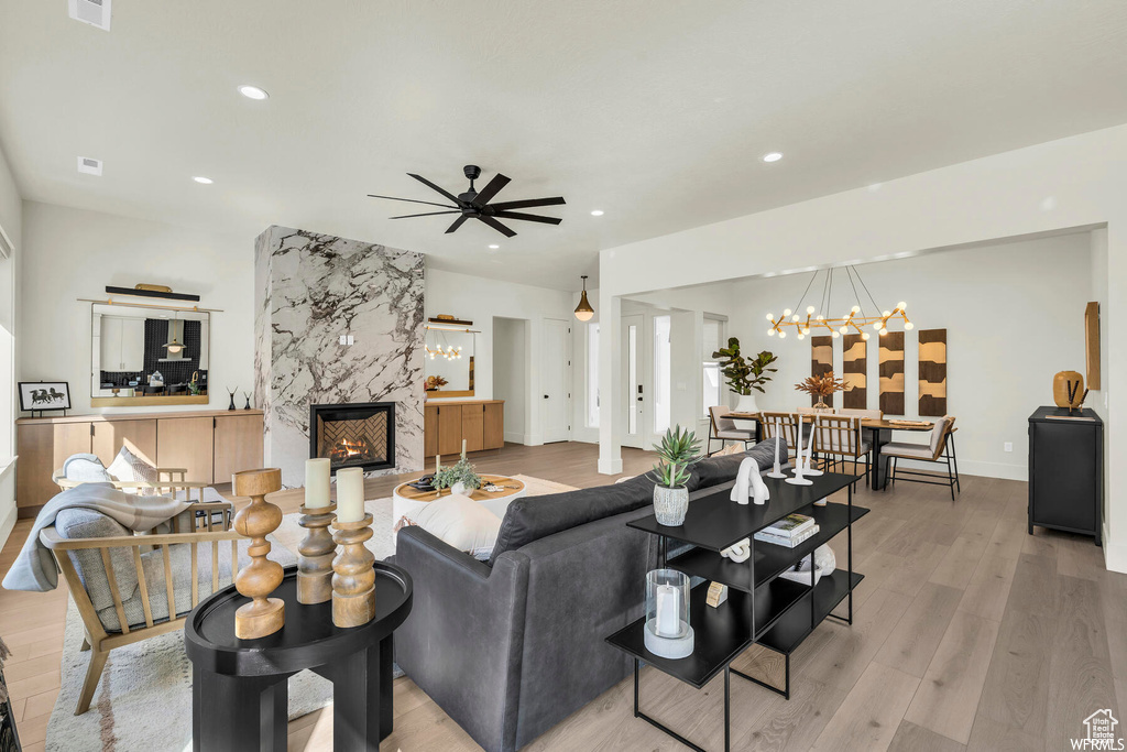 Living area featuring recessed lighting, a premium fireplace, a chandelier, a ceiling fan, and light wood-type flooring