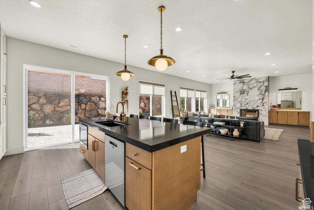 Kitchen featuring appliances with stainless steel finishes, dark countertops, recessed lighting, a high end fireplace, and wood finished floors