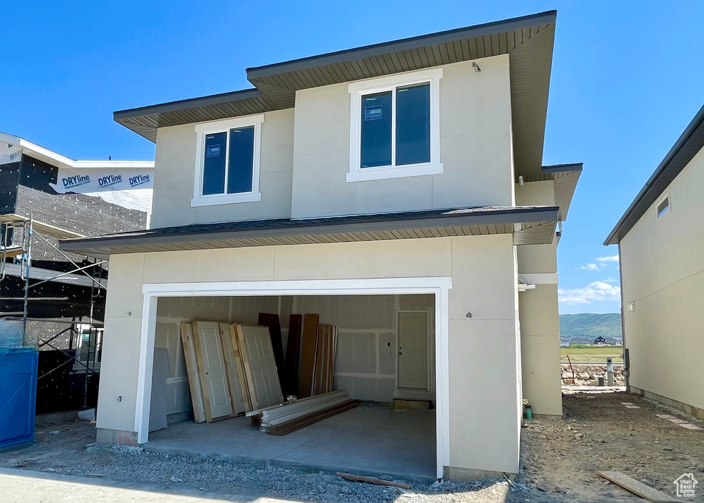 Back of house featuring a garage, stucco siding, and a mountain view