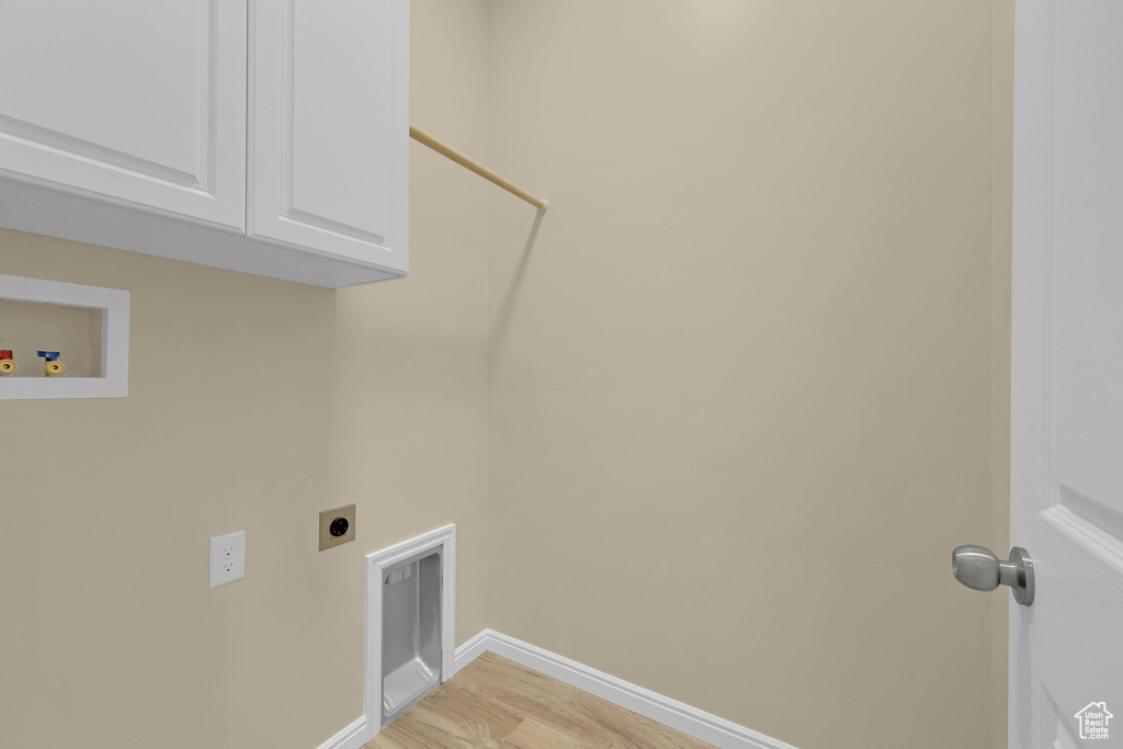 Laundry area with hookup for an electric dryer, light wood-style flooring, cabinet space, and washer hookup