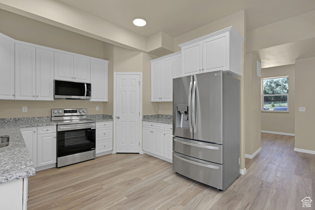 Kitchen featuring stainless steel appliances, white cabinetry, and light wood-style flooring