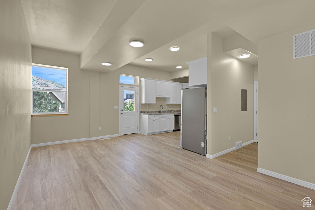Unfurnished living room featuring light wood-type flooring, recessed lighting, and electric panel