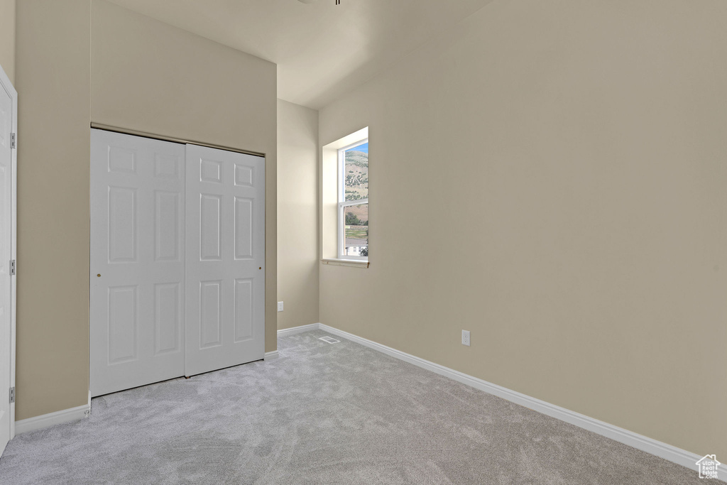 Unfurnished bedroom featuring light carpet and a closet