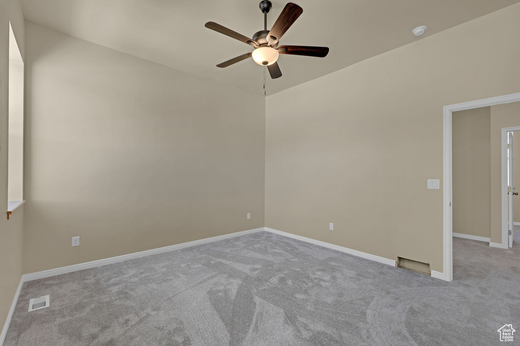 Carpeted spare room featuring ceiling fan and a smoke detector