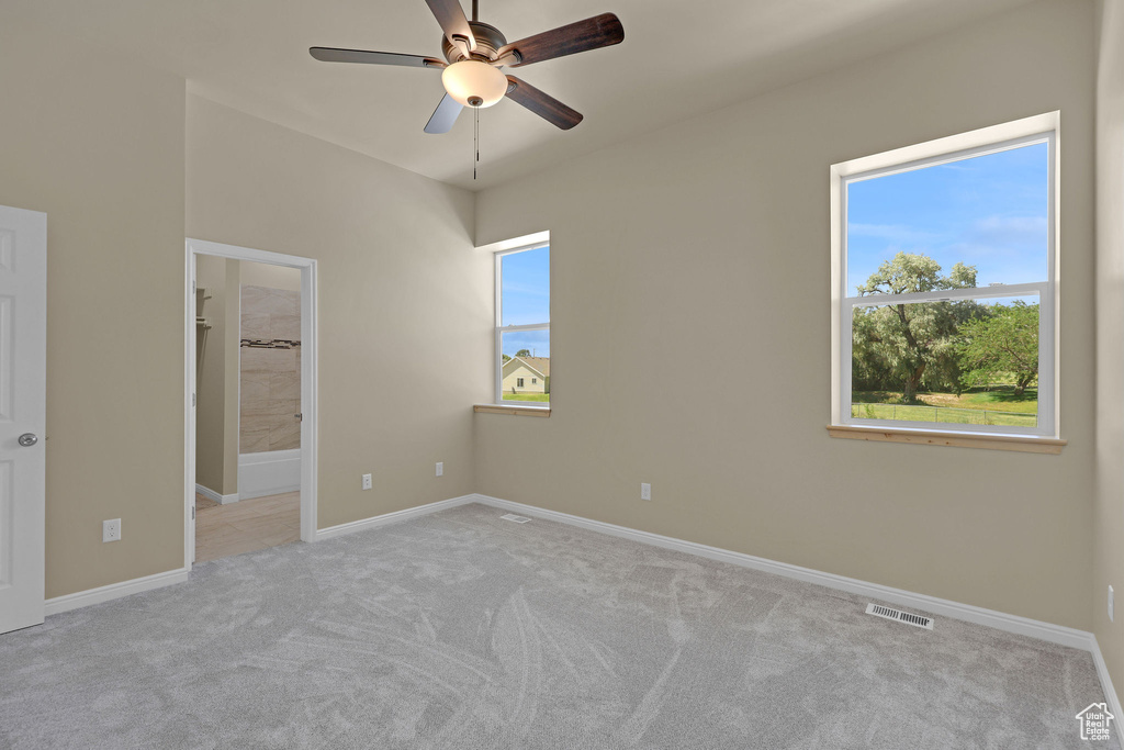 Unfurnished bedroom with carpet floors, ensuite bathroom, and ceiling fan