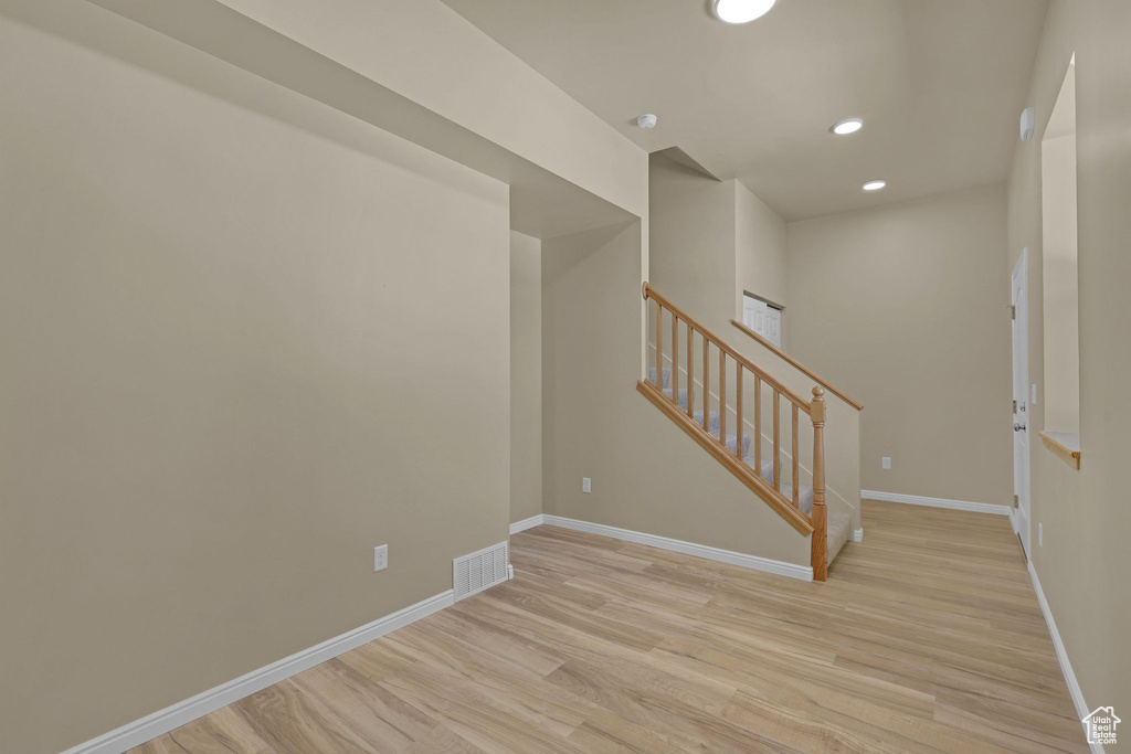 Empty room with light wood-type flooring, stairway, and recessed lighting