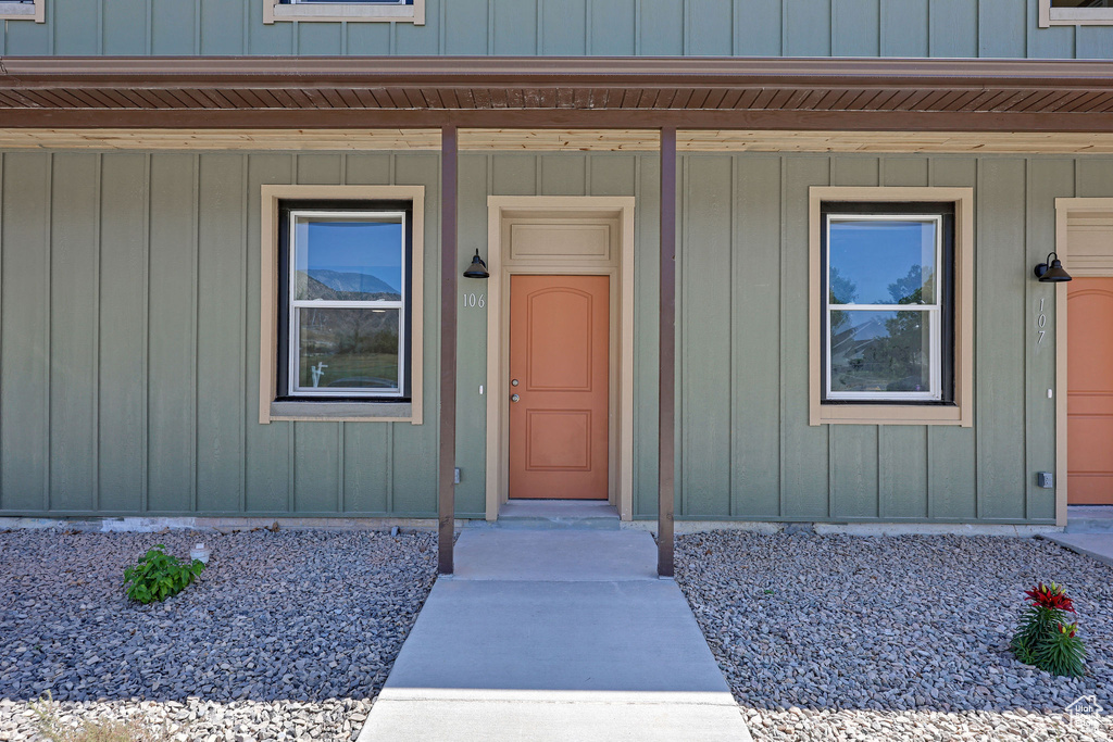 View of exterior entry featuring a porch and board and batten siding