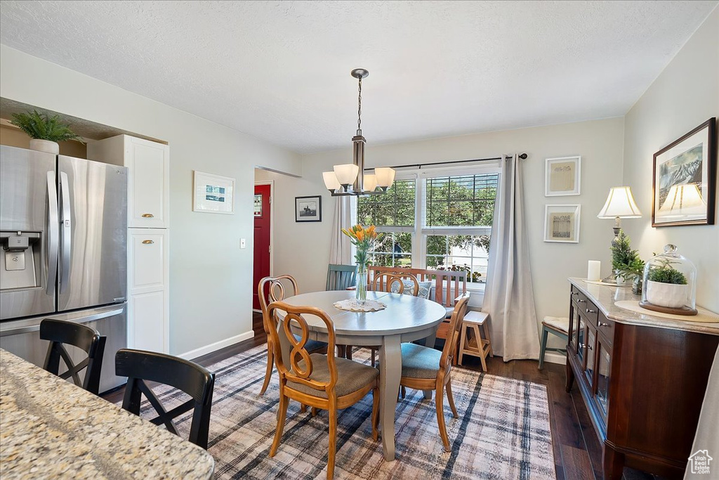 Dining room with a chandelier and dark wood-style flooring