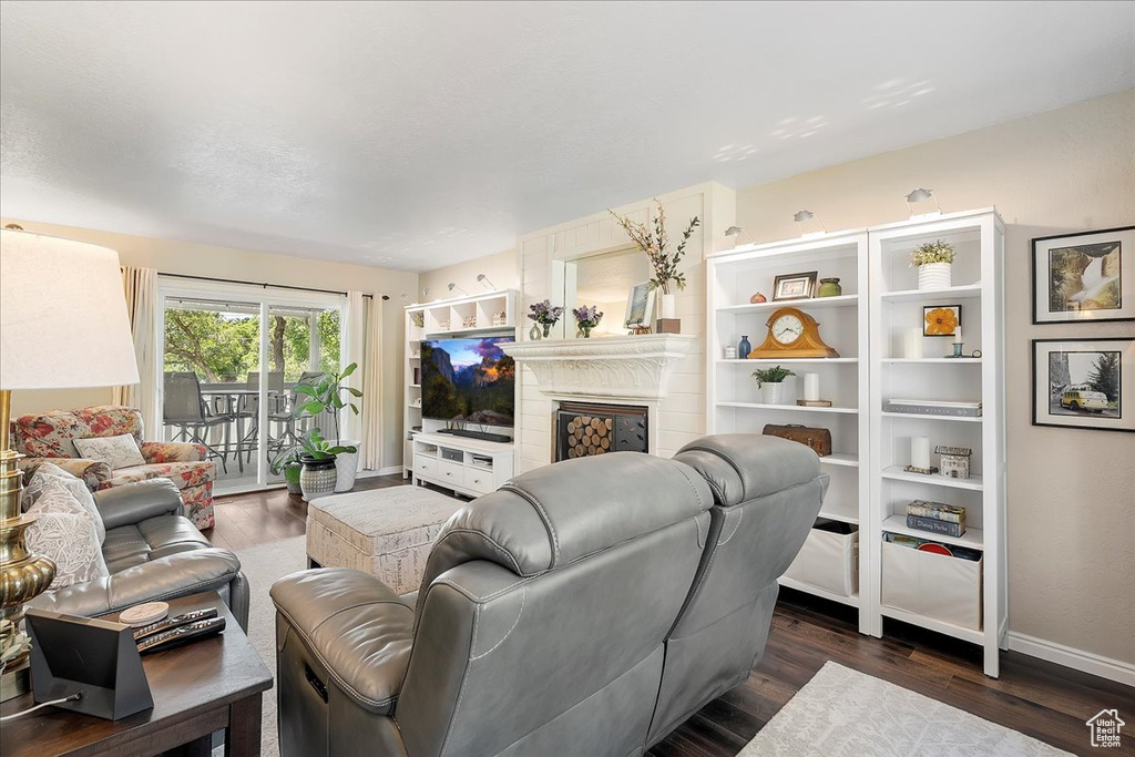 Living room with dark wood-type flooring and a fireplace