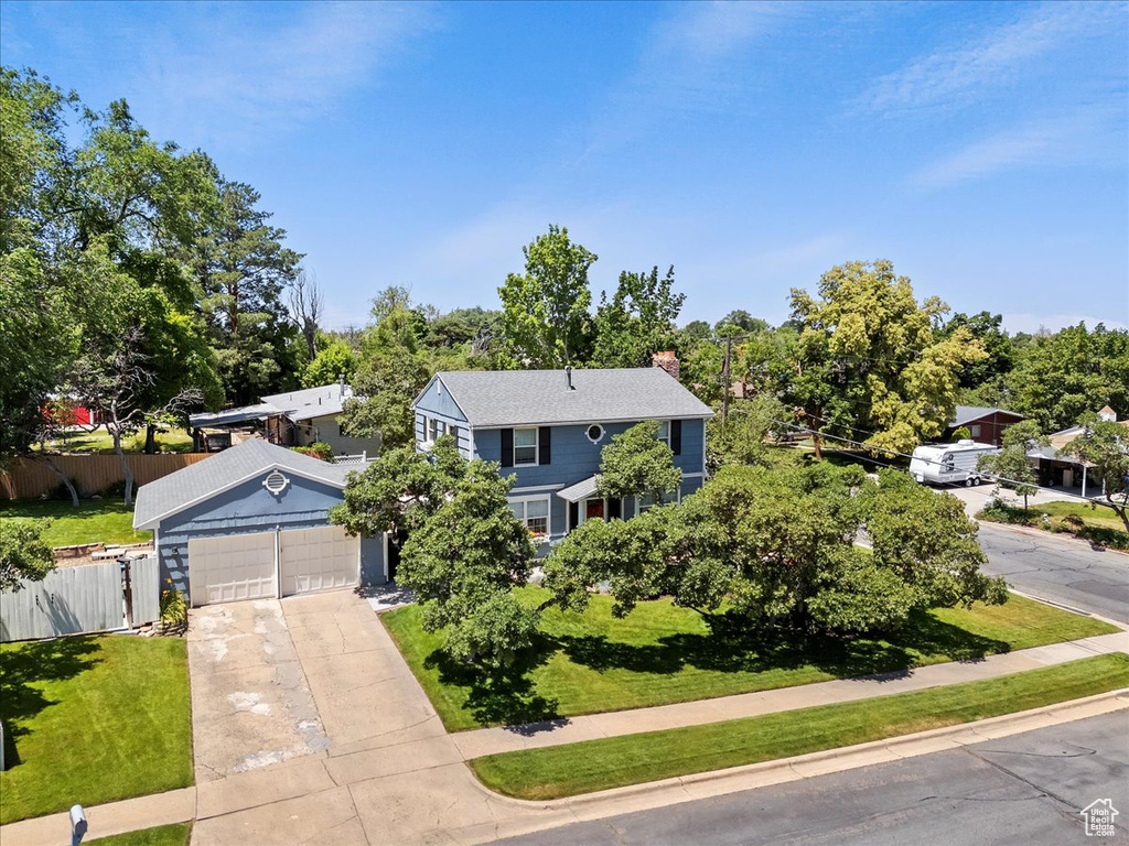 View of front facade with a garage, concrete driveway, a chimney, and view of wooded area