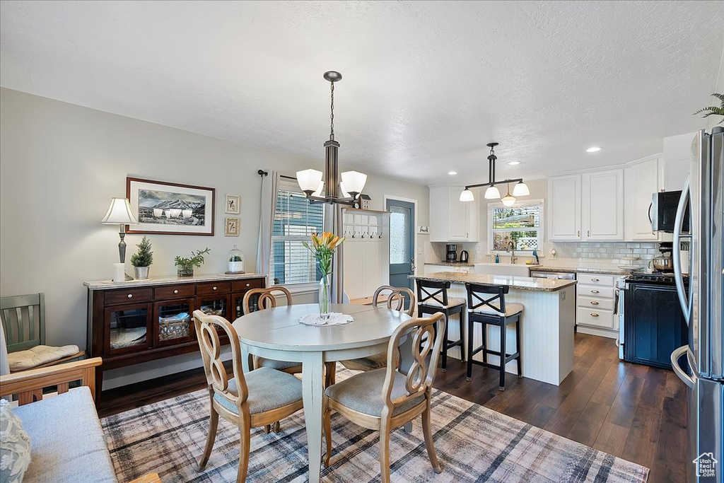 Dining room with a chandelier, dark wood finished floors, and recessed lighting