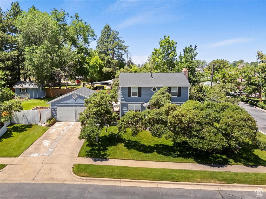 View of front of home featuring driveway, a chimney, and view of scattered trees