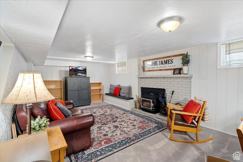 Carpeted living room featuring a wood stove and a textured ceiling