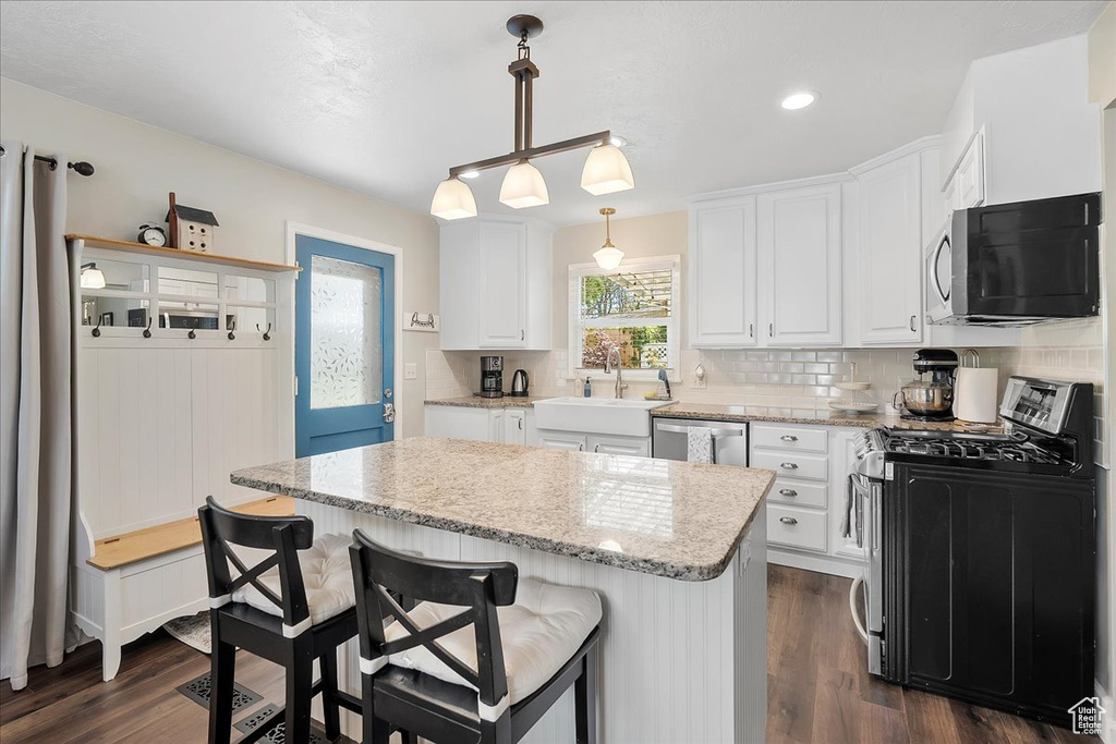Kitchen with appliances with stainless steel finishes, white cabinetry, a center island, dark wood finished floors, and recessed lighting