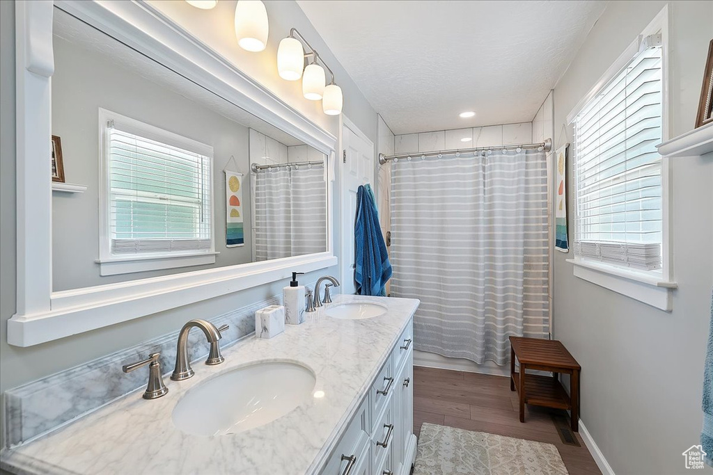Bathroom with double vanity, healthy amount of natural light, wood finished floors, a shower with shower curtain, and recessed lighting