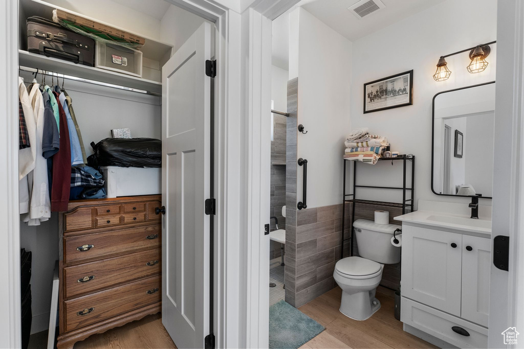 Full bathroom with vanity, a stall shower, wood finished floors, and tile walls