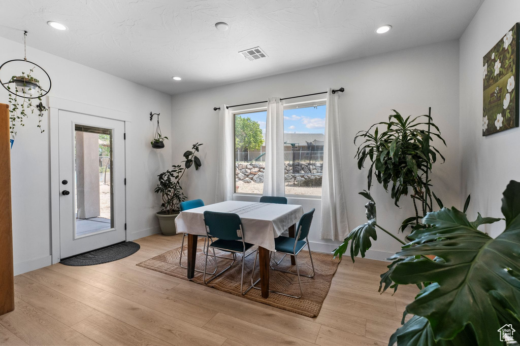 Dining room with light wood finished floors and recessed lighting