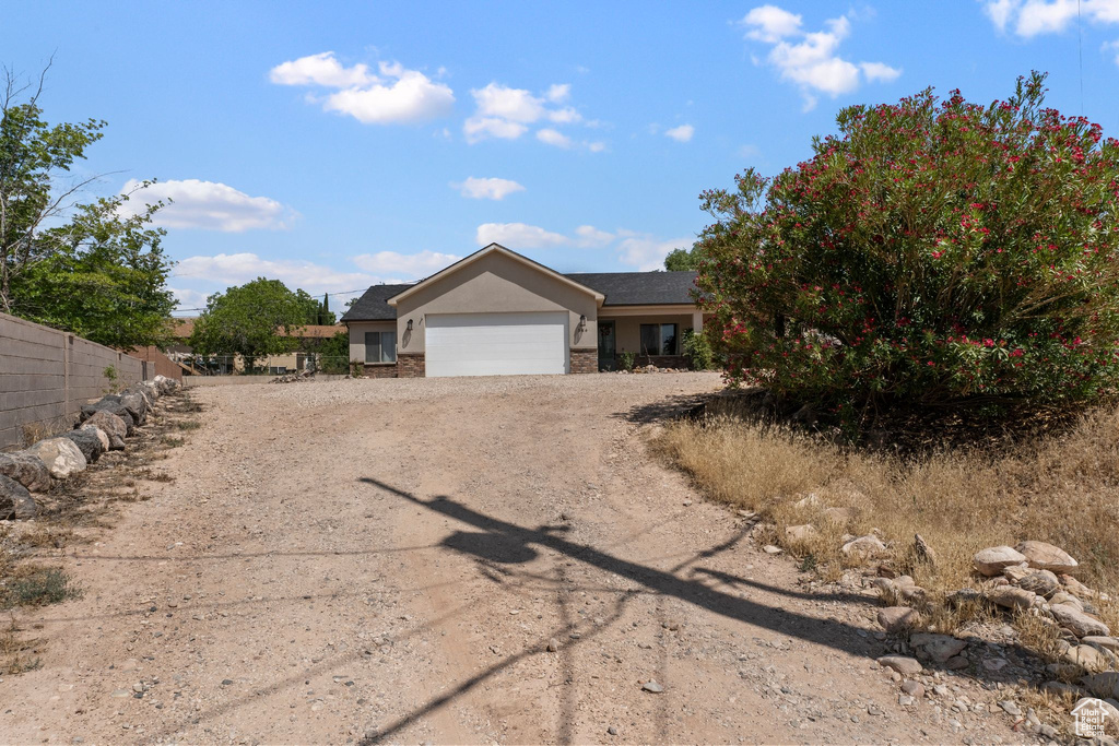 View of front facade featuring stucco siding, a garage, driveway, and stone siding