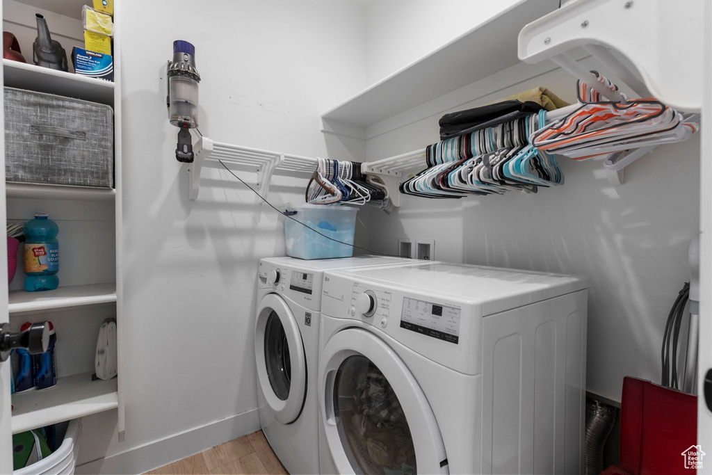 Laundry area with washer and clothes dryer and light wood-type flooring