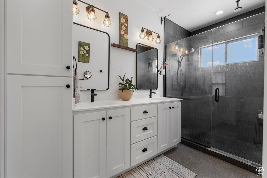 Bathroom featuring a shower stall, double vanity, and tile patterned flooring