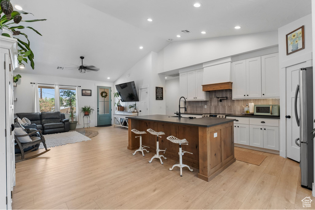 Kitchen featuring dark countertops, custom exhaust hood, open floor plan, freestanding refrigerator, and recessed lighting