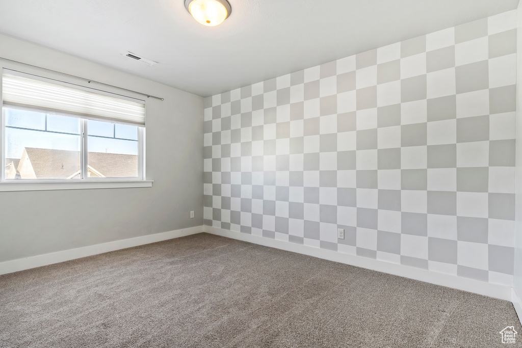 Carpeted spare room featuring baseboards
