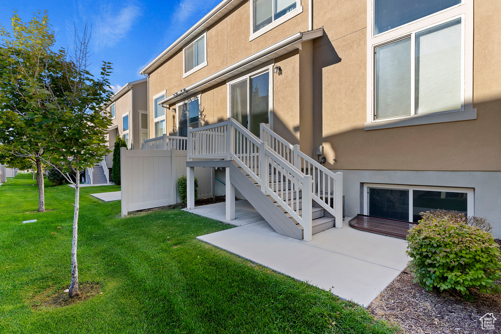 Back of property featuring stucco siding, a patio area, a lawn, and stairs