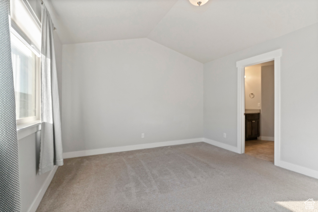 Unfurnished bedroom featuring carpet floors, lofted ceiling, and ensuite bath