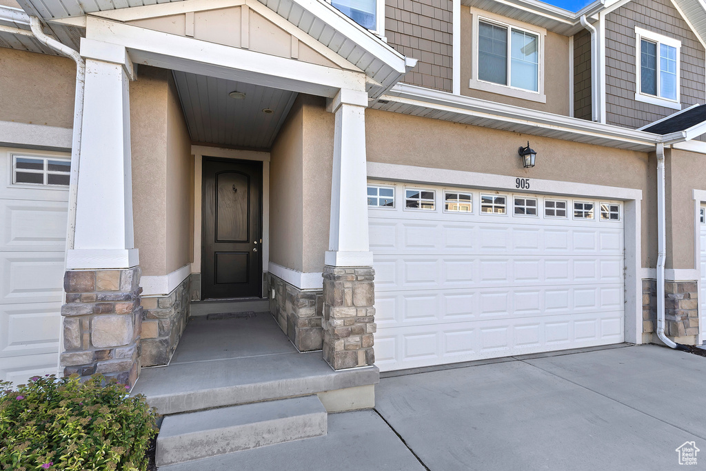 Entrance to property with stone siding, stucco siding, and driveway