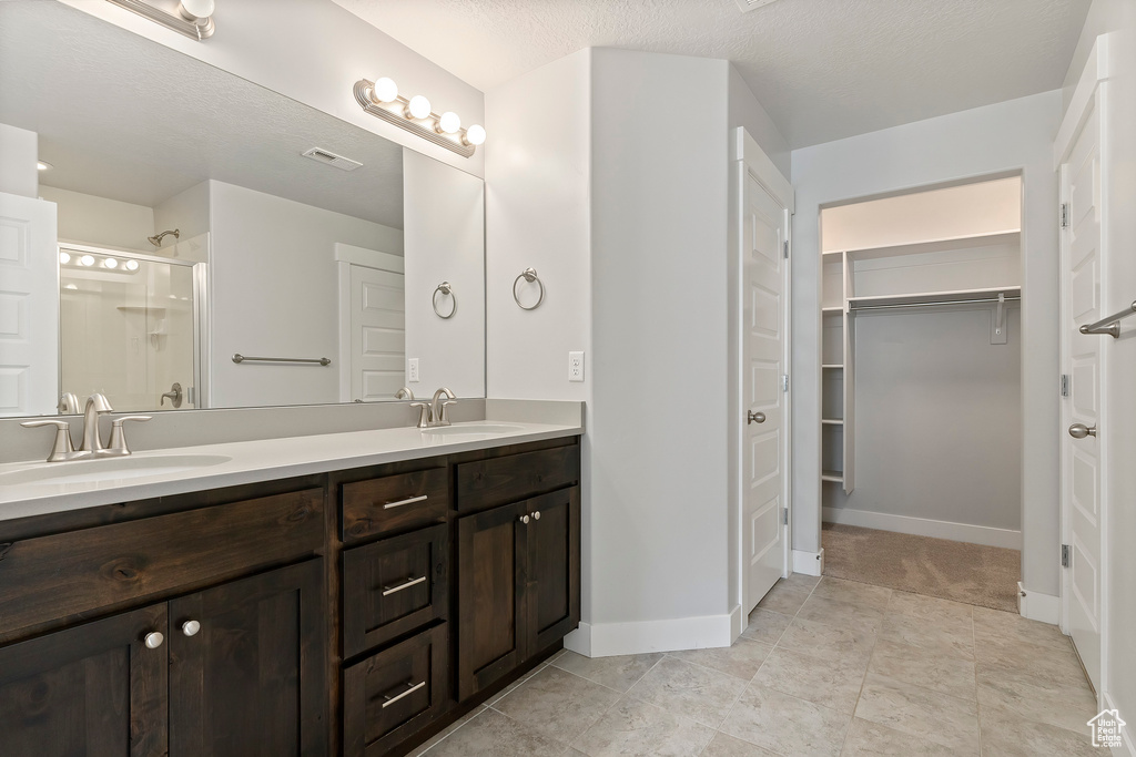 Bathroom featuring double vanity, a stall shower, and a spacious closet