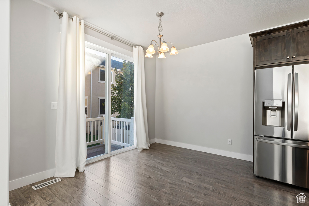 Unfurnished dining area featuring a chandelier and dark wood-style floors