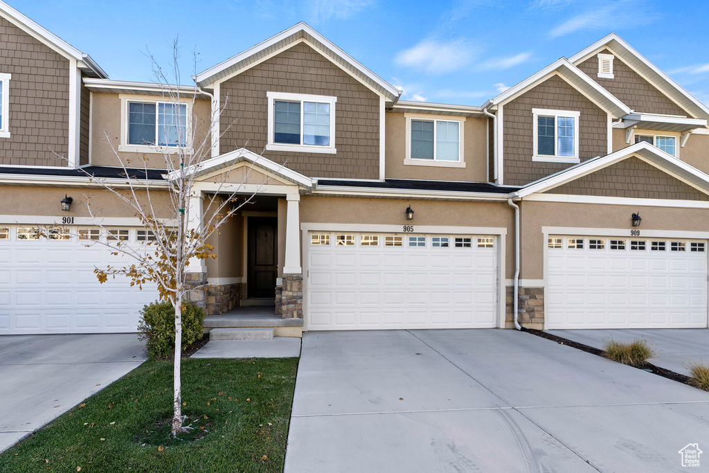 View of front facade with stone siding, concrete driveway, stucco siding, and an attached garage