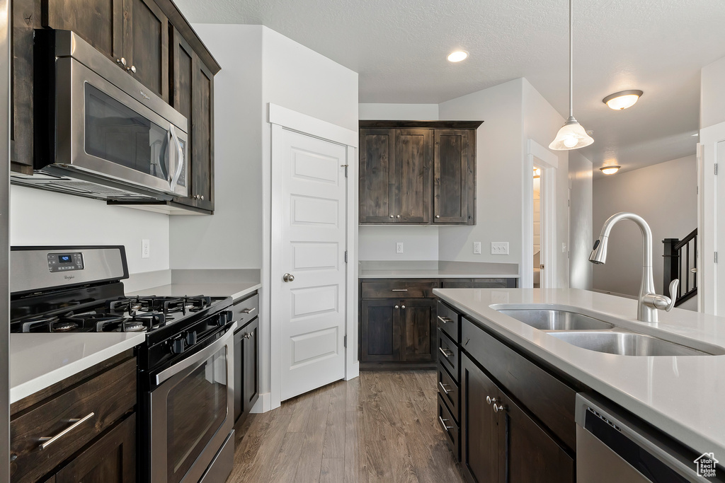 Kitchen with stainless steel appliances, dark wood-style floors, dark brown cabinets, light countertops, and recessed lighting