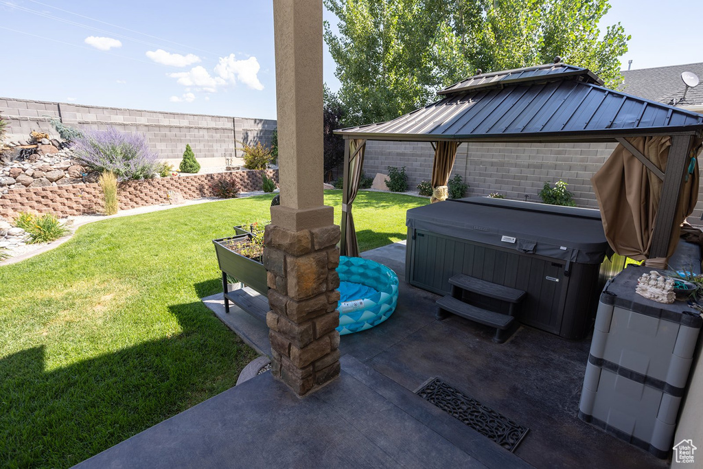 Fenced backyard with a gazebo, a hot tub, and a patio