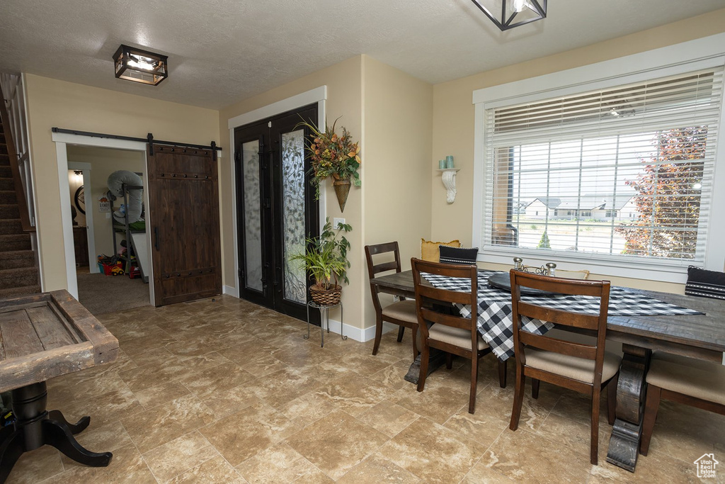 Dining area featuring a barn door, light stone finish floors, and stairway