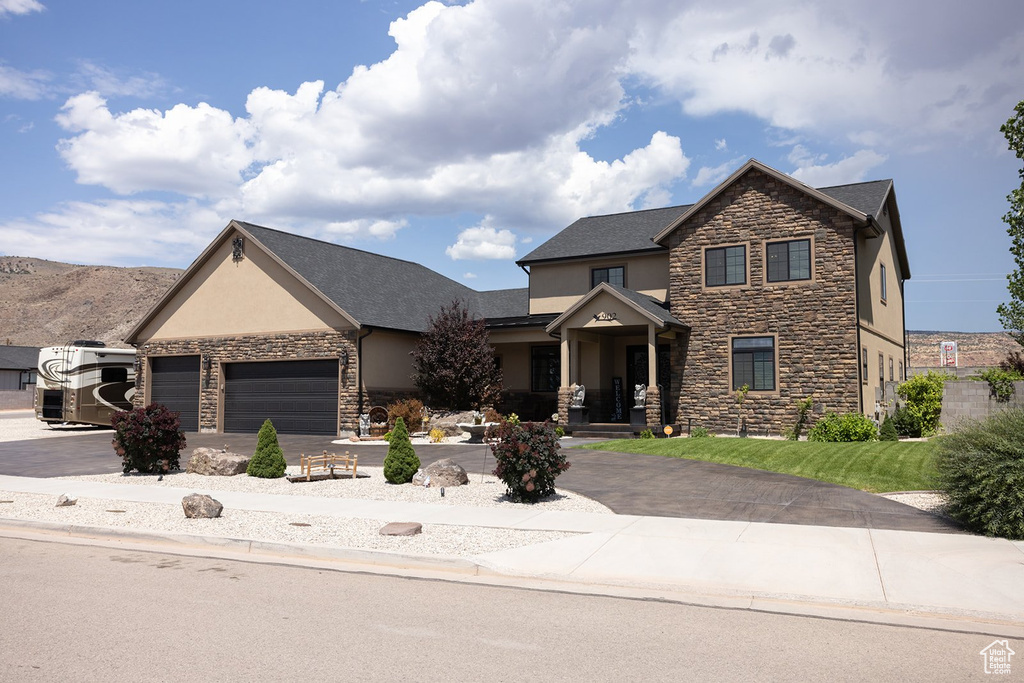 View of front of home with stone siding, stucco siding, driveway, and a garage