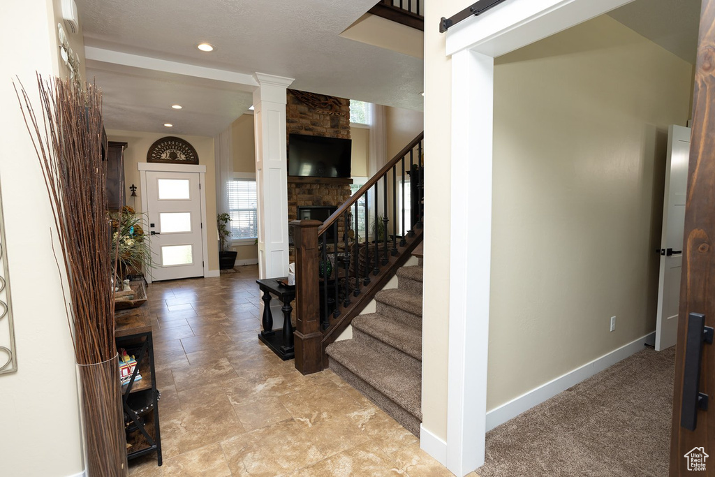 Entrance foyer with stairway, decorative columns, recessed lighting, and a large fireplace
