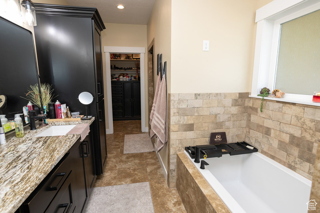 Bathroom featuring vanity, a bath, and a walk in closet