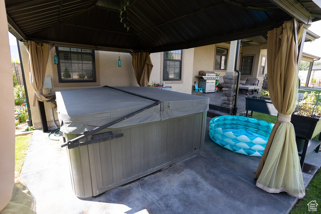 View of patio / terrace featuring a hot tub, a grill, and a gazebo