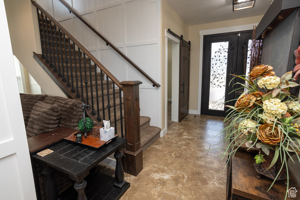 Foyer entrance featuring stone finish floors, stairway, and a barn door