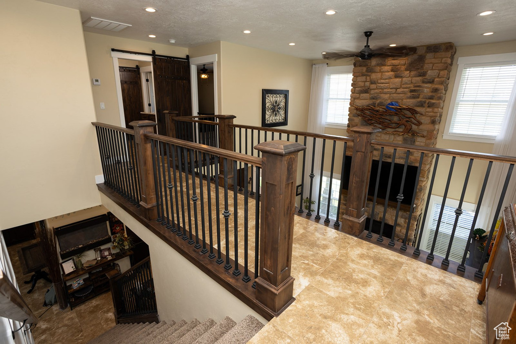 Staircase featuring a ceiling fan, recessed lighting, a textured ceiling, and a barn door